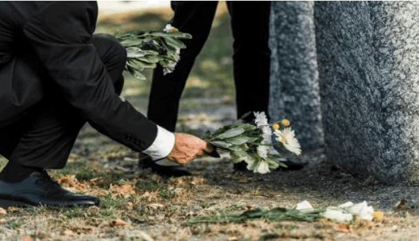 Pessoa depositando flores junto a um túmulo